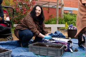 A person planting in compost on the micro-farm at Auxiliary