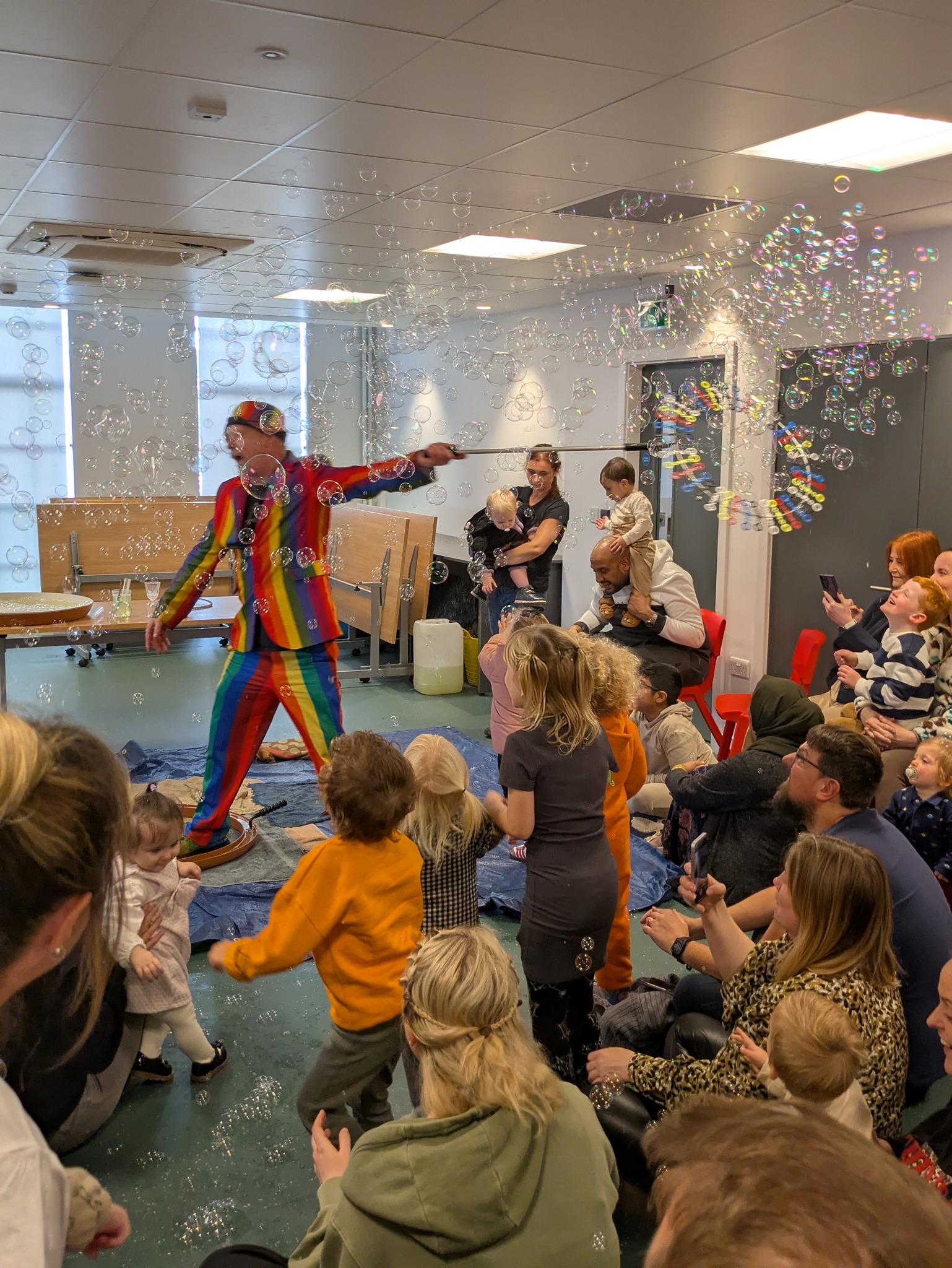 A man in colourful clothes entertains children with bubbles in middlesbrough central library