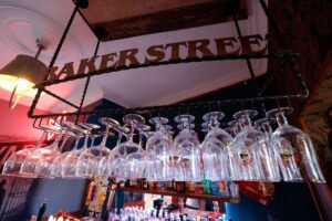 Beer glasses hanging upside down in a bar underneath the words baker street