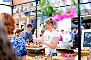 A person serving cakes on a sunny day at the orange pip market