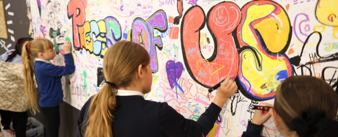children drawing on a mural that says 'pieces of us'