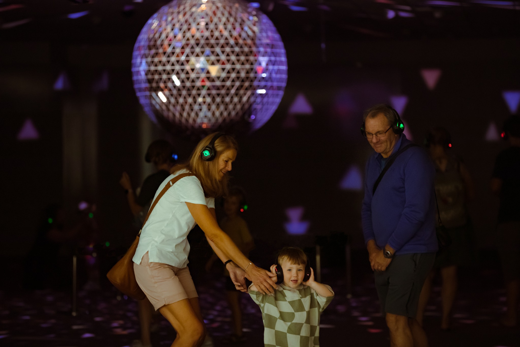Two parents and a toddler dancing around a glitter ball at Happy Rooms.
